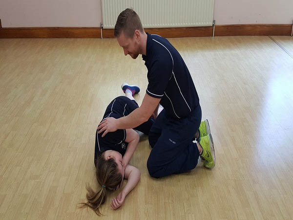 Trainee illustrates how to place a breathing casualty into the recovery position